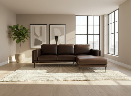 Brown leather sectional sofa on a concrete floor with a white backdrop