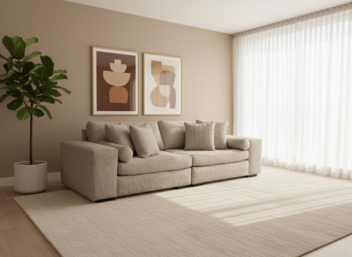 Gray sofa with patterned cushions in a room with gray walls and carpet.