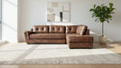 Brown leather sectional sofa in a modern living room with a plant and abstract art on the wall.