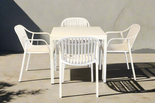White outdoor table with four matching chairs on a concrete patio.