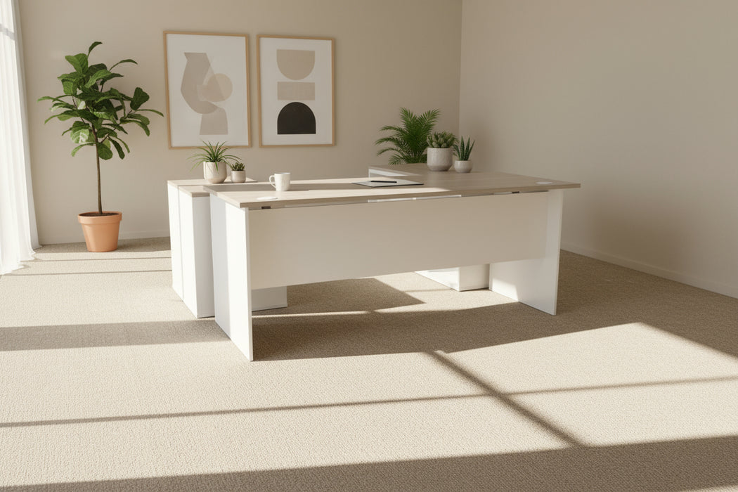 L-shaped desk with wooden top and white sides on a gray carpeted floor.