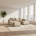 Gray sectional sofa against a gray wall with a white curtain in the background.