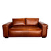 A brown leather loveseat sofa photographed from above on a white sheet, with a tiled wall and gray floor visible around it.