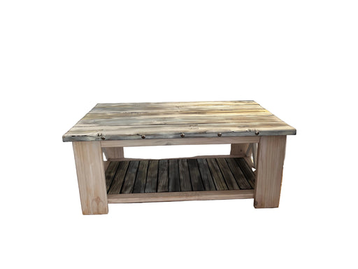 A rustic rectangular wooden coffee table with a weathered top, a lower slatted shelf, and a light natural wood frame, set against a draped white fabric backdrop.