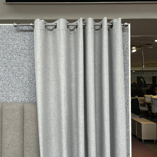 Gray curtain with grommets in a room with a textured wall and furniture.