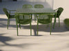 Green outdoor table and chairs set on a textured white surface