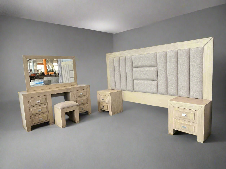Beige bedroom furniture set with a bed, dresser, and mirror in a room.