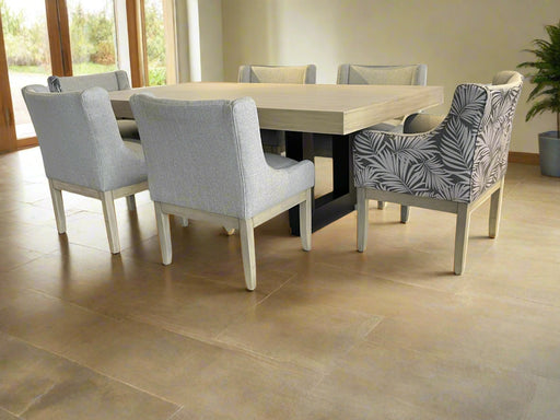 Dining table with six chairs, including a patterned chair, on a white draped background.