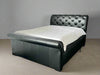 Black leather bed with white mattress against a gray wall