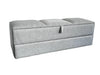Gray upholstered storage bench on a carpeted floor with a white sheet in the background