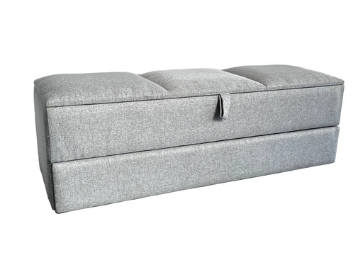 Gray upholstered storage bench on a carpeted floor with a white sheet in the background