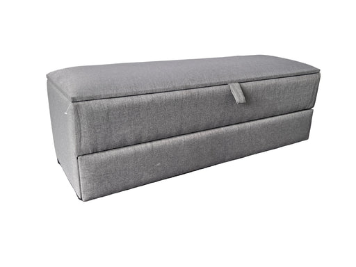 Gray storage ottoman on a purple floor with a white draped background