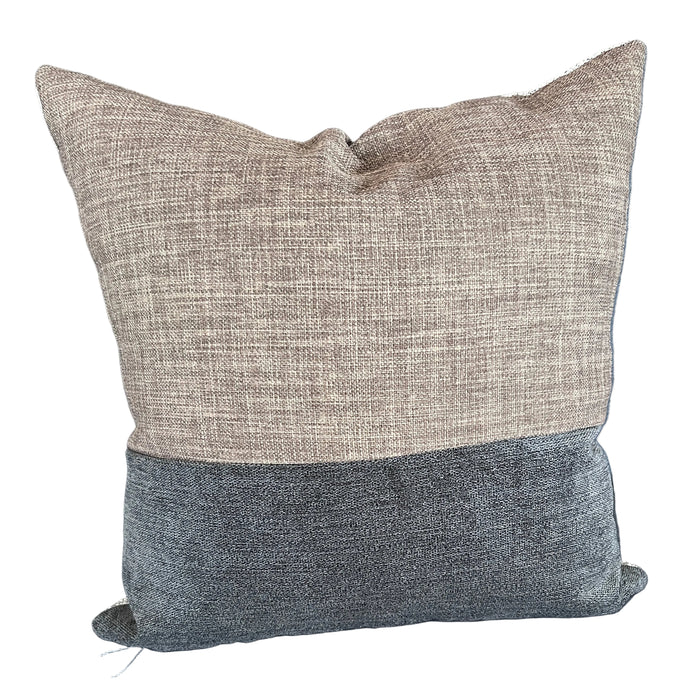 Two textured pillows on a blue sofa with a visible tag.