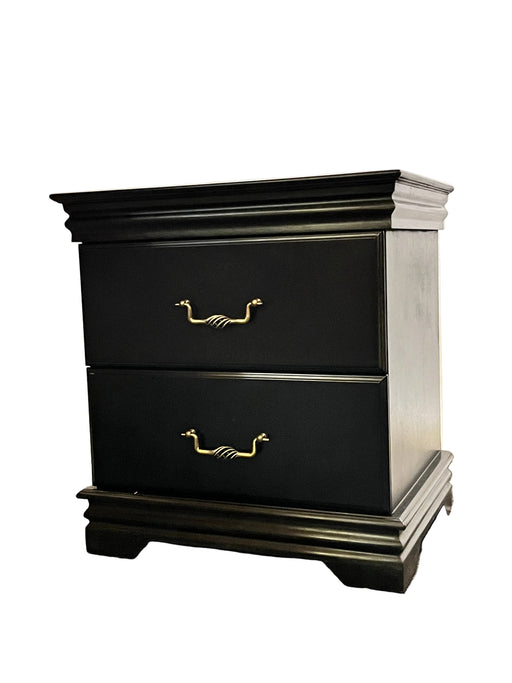 Black cabinet with gold handles on a textured wall.