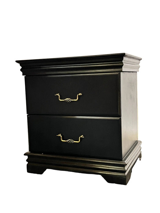 Black cabinet with gold handles on a textured wall.