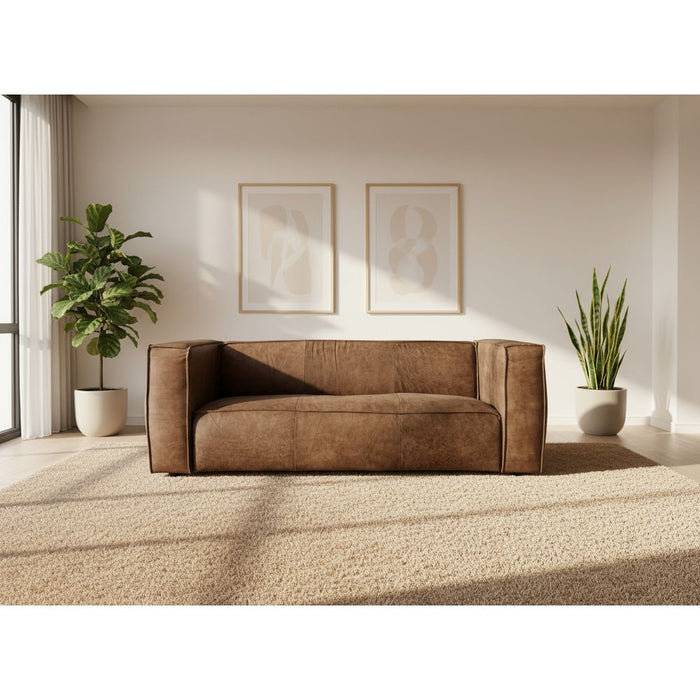 Brown sofa being set up with a white backdrop in an indoor setting