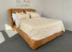 Brown bed frame with beige bedding against a plain background