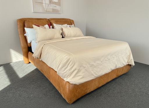 Brown bed frame with beige bedding against a plain background