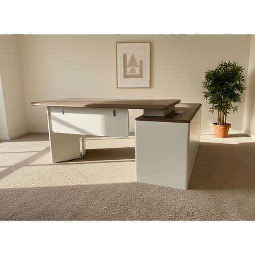 White office desk with a brown top on a gray floor.
