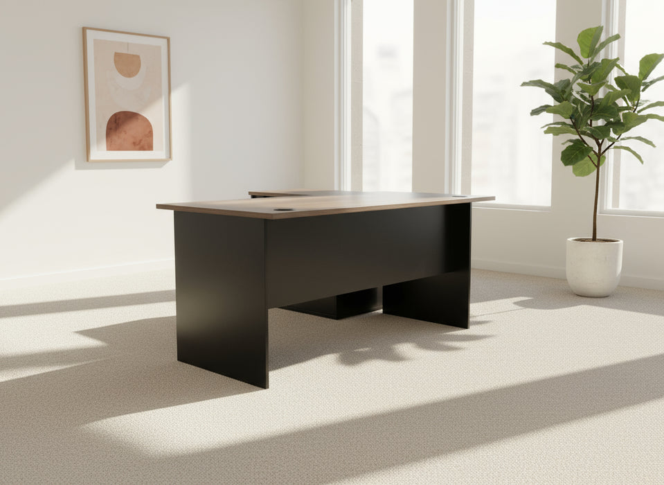 Black office desk with a gray carpeted floor and white draped backdrop