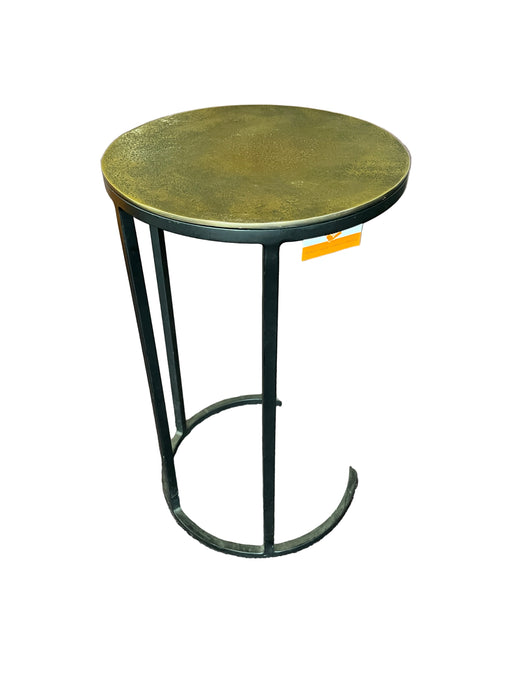 Round metal table with a black metal base on a textured floor