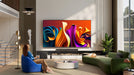 Hisense TV | Woman sitting on a blue chair in a modern living room with a colorful abstract painting on the wall. | Nictus Namibia